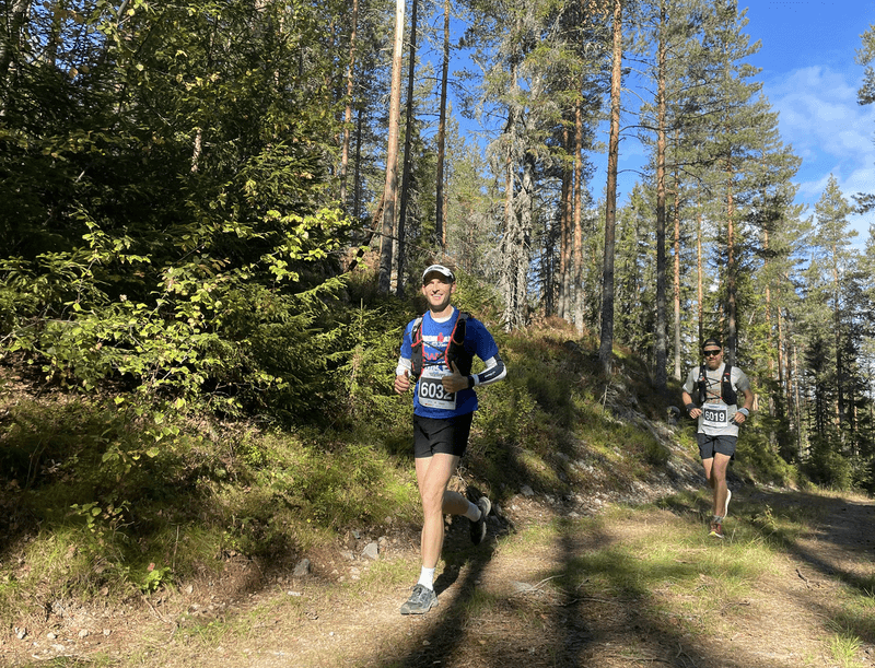 running through the Nordmarka pine forest around the halfway point of the race, with a competitor close behind